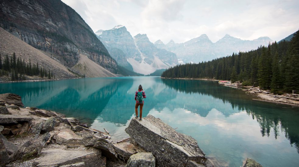 Female hiker stood on the edge of a lake surrounded by mountains